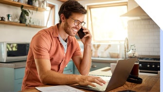 Man smiling at laptop while on the phone