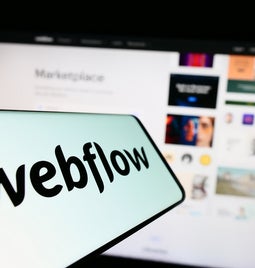 webflow logo with computer screen out of focus in background