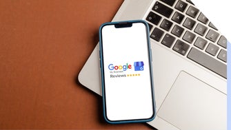 Phone showing Google Reviews logo, resting on a laptop