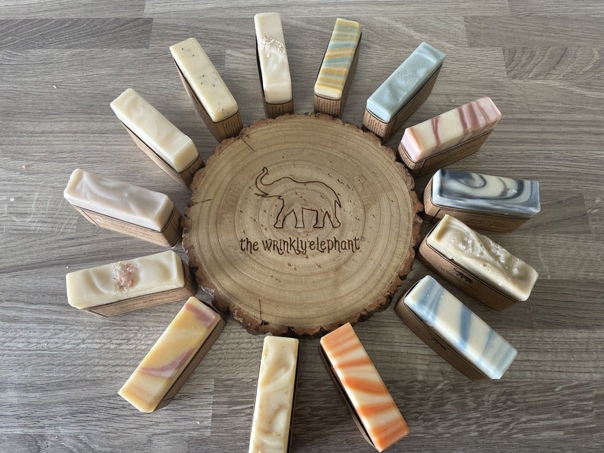 Circle of soap bars displayed around a circle of wood with The Wrinkly Elephant engraved into the wood