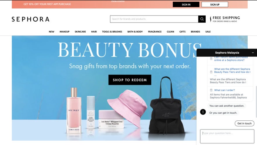 A blue Sephora page with the headline "Beauty Bonus" and fancy toiletries, a bag, and a pick bucket hat. On the right is a pop-up chat.
