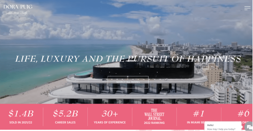 Luxury real estate homepage for Dora Puig featuring a coastal view, with a motto "Life, Luxury and the Pursuit of Happiness," and key achievements.