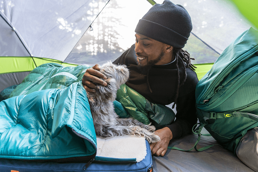 Man in a tent with a dog using a pet bed/sleeping bag